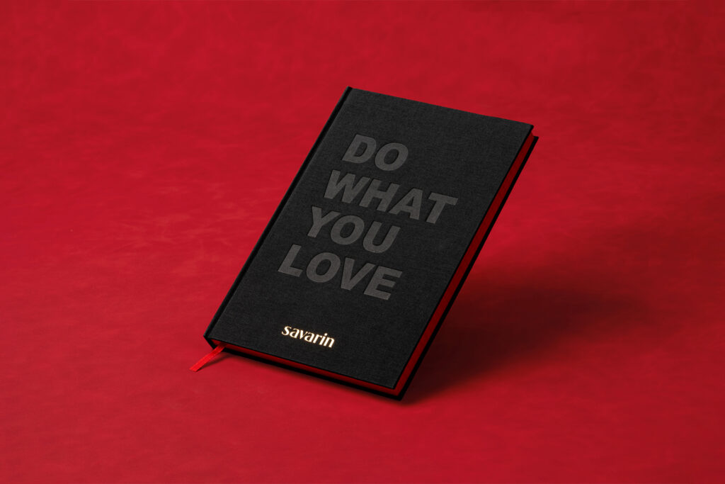 black clothbound notebook on red background with debossed letters